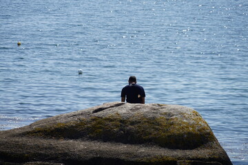Homme seul assis sur un rocher .