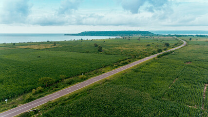 Aerial view of the road between corn field with beautiful beach and sea in Samota, Sumbawa, Indonesia