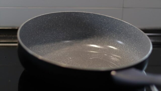 Pouring cooking oil in a frying pan. Preparing a meal.