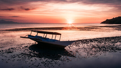 Beautiful beach with wooden boat and low tide water at sunset time in Ai Lemak Beach, Sumbawa, Indonesia