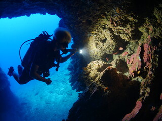 Fototapeta na wymiar cave diving underwater scuba divers exploring caves ocean scenery sun beams and rays background