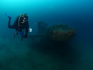 Naklejka na ściany i meble wreck dive underwater fish around ship wreck metal on ocean floor with scuba divers 