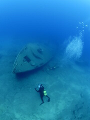 Fototapeta premium wreck dive underwater fish around ship wreck metal on ocean floor with scuba divers 
