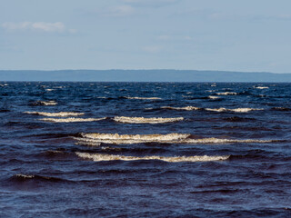 Waves with white foam on a lake with shallow depth in a sunny, windy day in Karelia, northwest of...
