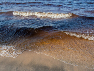 Waves with white foam on a lake with shallow depth in a sunny, windy day in Karelia, northwest of...