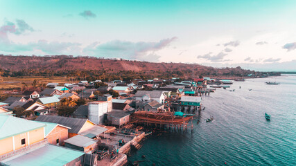 Fototapeta na wymiar Aerial view of fisherman village in Labuan Jambu, Sumbawa, Indonesia. Traditional house with wooden pier on sea water with blue sky