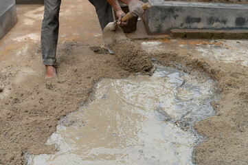 Indian labour mixing cement and water manually on floor using a shovel. Stock image.