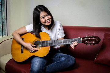 Fototapeta premium a photo of a woman sitting and playing an acoustic guitar