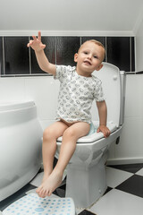 baby sit on a kid bathroom accessory toilet. A toddler confronts the challenge that awaits him in...