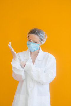 Portrait of a doctor, a young woman in a protective medical mask on her face and a cap on her head. looking seriously into the frame. on a yellow background. surgeon. ambulance paramedic. copy space