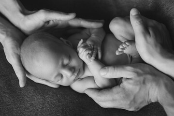newborn baby lying on the hands of parents. Imitation of a baby in the womb. beautiful little girl sleeping lying on her back
