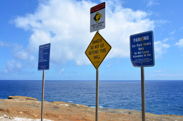 Blue ocean & blue sky beyond the three sign poles at Lanai Lookout, Honolulu, Oahu Island, Hawaii