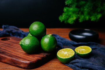 fresh limes with slice and leaves on dark background
