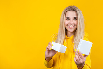 Portrait of young happy caucasian blonde woman in yellow sportive suit, open a white gift box