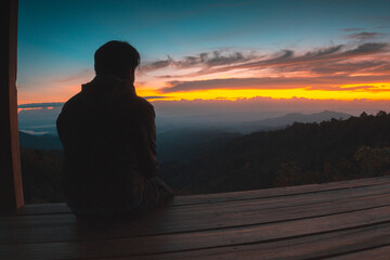 A man sit alone looking at the rising sun at Batu Dulang Village, Sumbawa, Indonesia