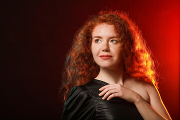 Portrait of beautiful redhead woman on dark background