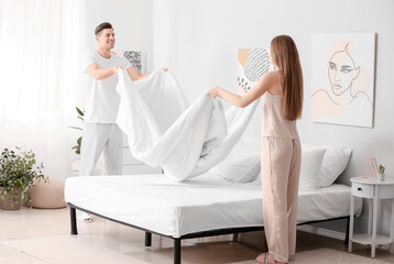 Morning of happy young couple changing bedclothes at home