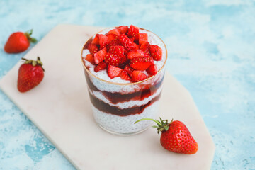 Tasty strawberry dessert in glass on color background