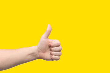 Closeup of male hand showing thumbs up sign isolated on yellow background with place for text. Banner. Good day.