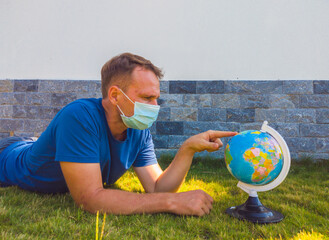 Man wearing Face Mask holding the Earth globe world map in hand. Quarantine yourself to protect...