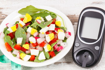 Glucometer for checking sugar level and fresh salad with eggs and vegetables, diabetes and healthy nutrition concept