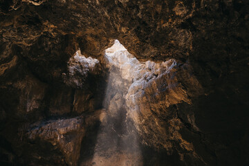Fototapeta na wymiar light falls through the cave opening from above