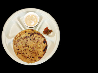 Paratha chai with pickle in plate morning breakfast in india over dark black background with space for text