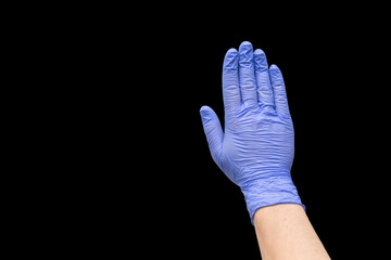 Hand of a white-skinned man in a blue glove isolated on a black background. A photograph may indicate a stop sign, closed area, end, caution or danger.