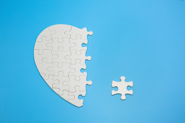 Unfinished white jigsaw puzzle pieces on blue background,  Copy space.