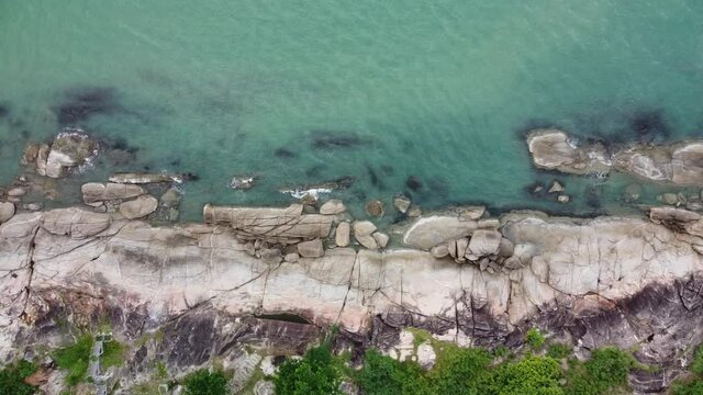 Aerial view of rock stone beach with turquoise water. Panning camera.