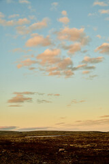 Beautiful landscape with blue sky, white clouds, sunset and field or tundra.
