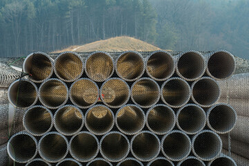 Stack of corrugated pipe covered with black mesh at new construction site