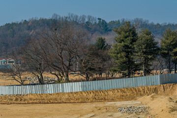 Grove of trees surrounded with aluminum wall for preservation at new construction site.
