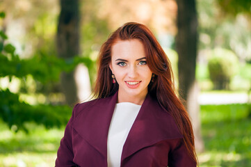 Closeup outdoors portrait of young stylish readhead woman with bright trendy makeup in red leather jacket with shallow depth of field