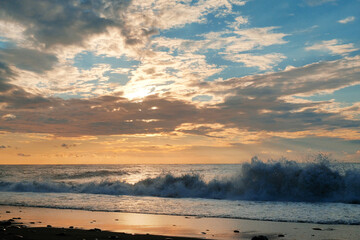 Obraz premium Splashing sea waves crashing on the shore with beautiful cloudy sky background