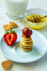Trendy food - pancake cereal. Stack of mini cereal pancakes with strawberries and milk