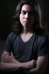 Obraz premium Portrait of young man with long hair in low key with Rembrandt lightning