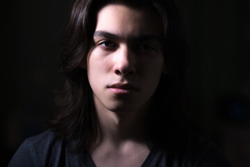 Portrait of young man with long hair in low key with Rembrandt lightning