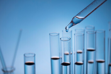 Coronavirus pandemic theme. Science research concerning fast covid tests and anti-covid vaccine. Beakers and test tubes on blue background.