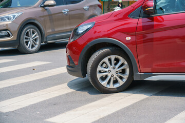 Obraz na płótnie Canvas Red car making a turn on crosswalk on street closeup
