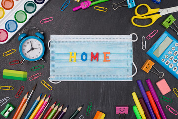 Home schooling concept. Top above overhead view photo of colorful stationery with mask and home word in center isolated on blackboard