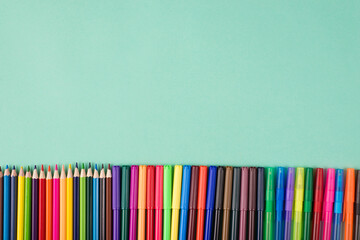 Top above overhead view flatlay photo of a row of multicolored crayons pens and markers isolated on...