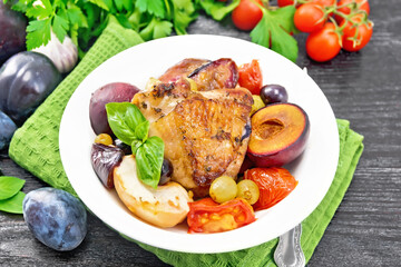 Chicken with fruits and tomatoes in plate on dark board