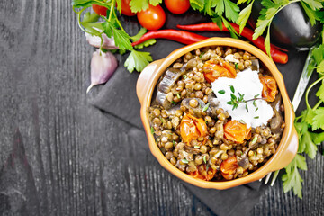 Lentils with eggplant and tomatoes in bowl on dark board top