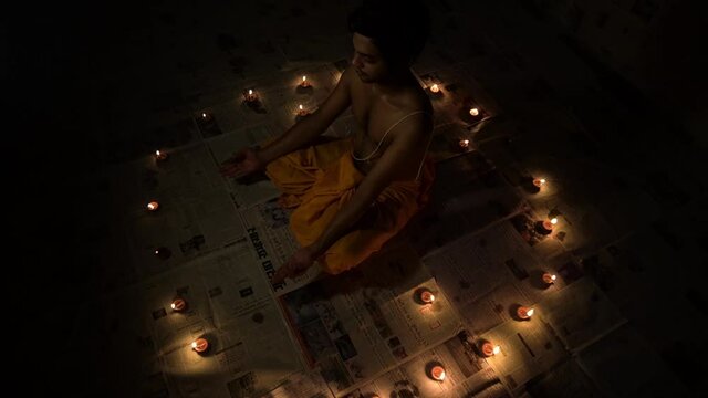 brahmin man between diya(oil lamp) and corona virus news papers. Brahmin is a varna in Hinduism specialising as priests, teachers and protectors of sacred learning across generations.