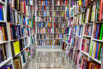 Shelves with books in a bookstore. Large selection of diverse literature. On the floor there is a marking for buyers to observe the distance during the period of the coronavirus epidemic. Blurred. - obrazy, fototapety, plakaty