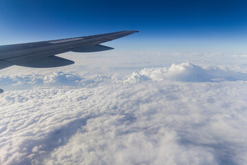 Fototapeta premium Blue sky with white clouds from the plane view.Cumulus clouds. Wing of the airplane can be seen.