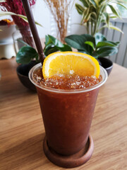black iced coffee and fesh orange juice in the cup, on the wooden table