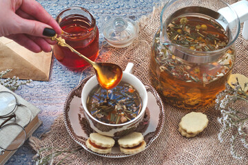 Cozy morning at home - old book and romantic letters to read, cup of delicious herbal tea with ginger and a jar of forest honey