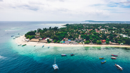 Tourism boats line the shores of Gili Air, Lombok, Indonesia. From above you have a clear view of the beautiful coral reefs and soft, white sand.